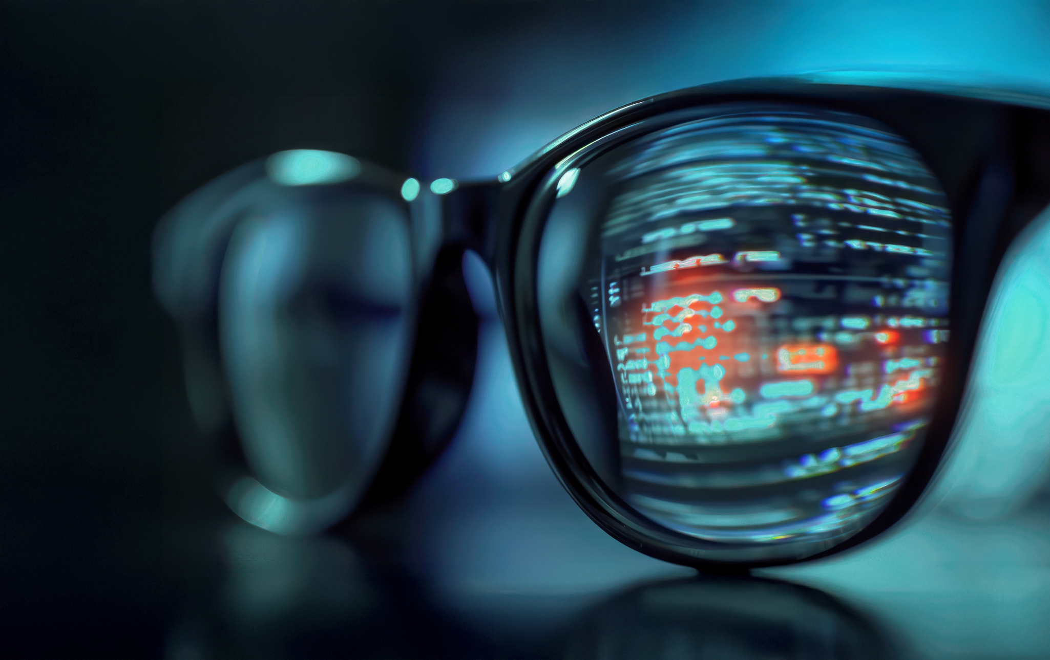 Glasses resting on a table with a data reflection visible in one lens.