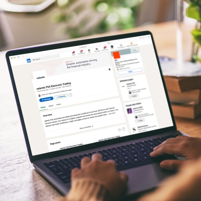 A laptop on a wooden table displaying the Electronic Trading LinkedIn start page.